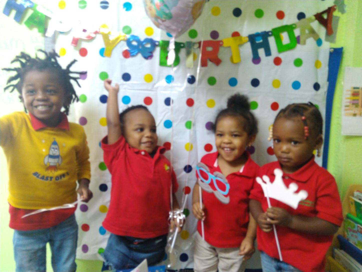 An image of four children standing side by side in an indoor setting. They are all looking at the camera wearing beige and...